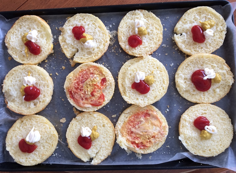 Photo of a glutino gluten free english muffins on a baking tray with condiments on them. 